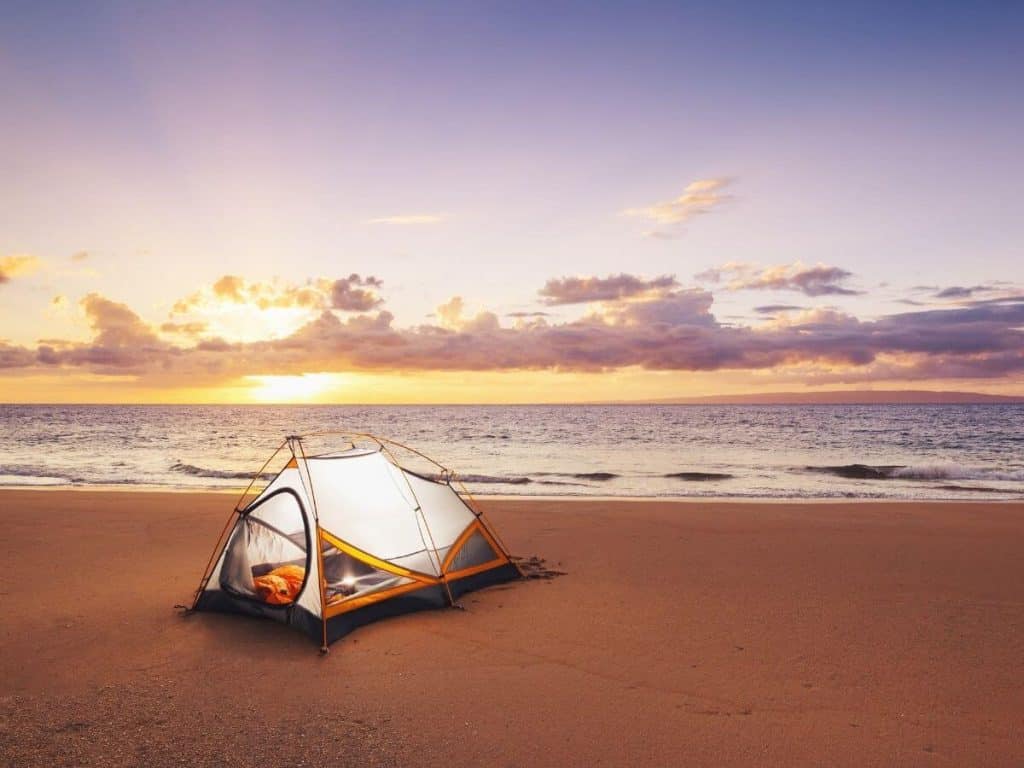 pismo beach camping at sunset with an orange and white tent on the beach.