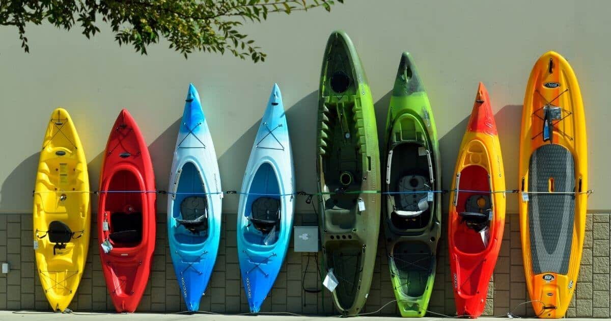 the best kayaks for camping lined up on a wall outsite.