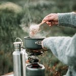 A Person Cooking Oatmeal using Portable Stove