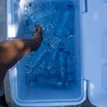 High-Angle Shot of a Person Getting Water Bottle in a Cool Box